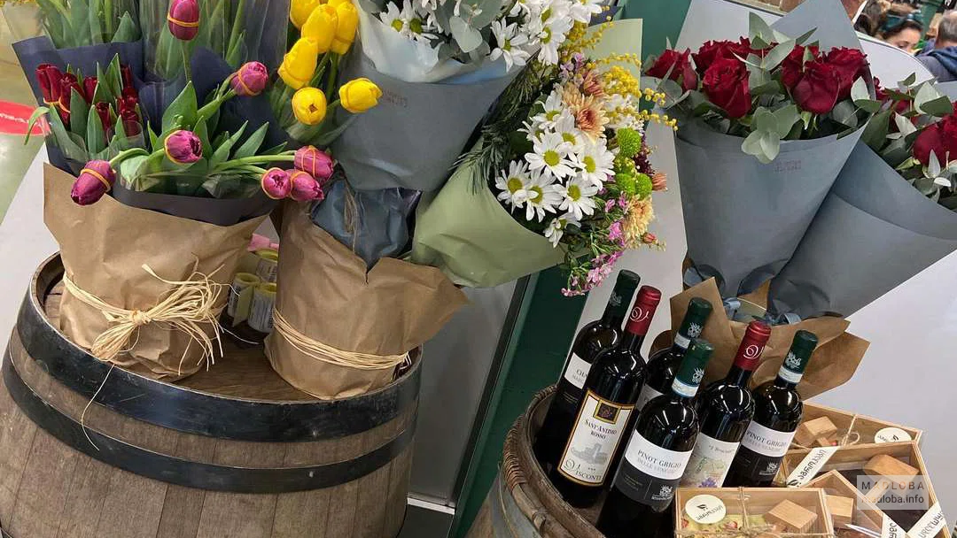 Букеты цветов и бутылки вина на бочках в магазине  "Агрохаб"