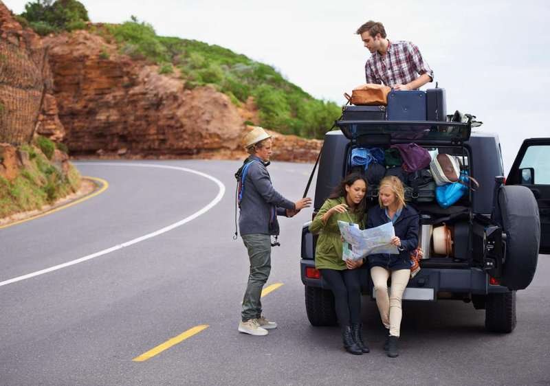 a group of young people near a car on the road