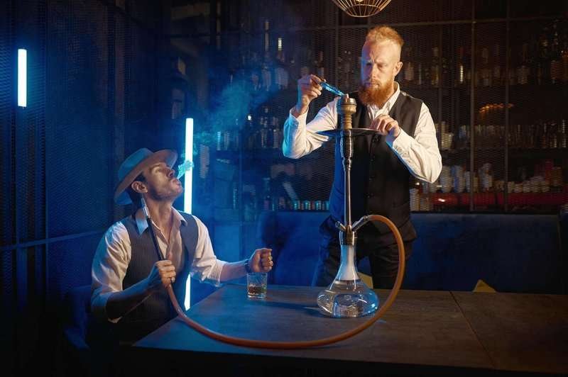 A hookah man fills a hookah at a bar