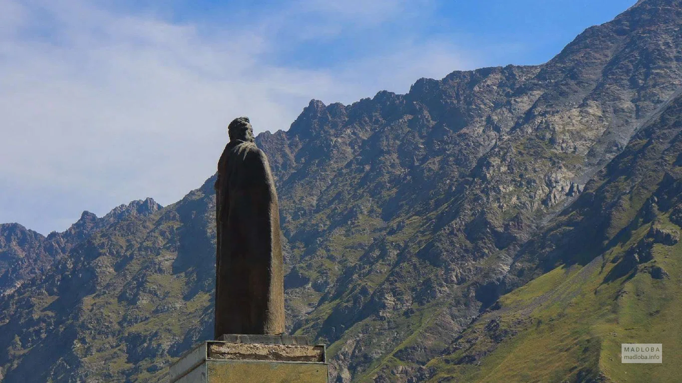 Памятник Александру Казбеги в Степанцминде на фоне гор