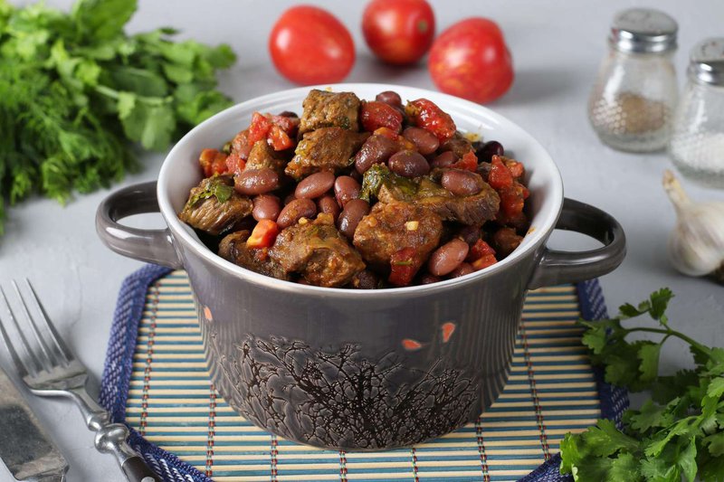 Лобио в глиняной посуде с зеленью и луком