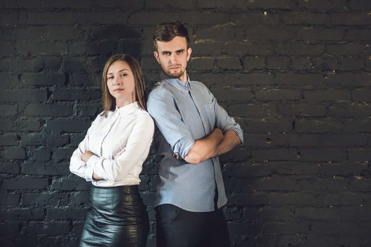 A business team of male and female young businessmen stands above a dark surface.