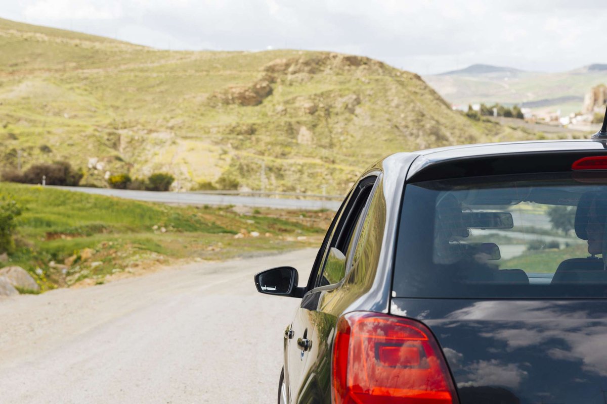 A car is driving along a road in nature