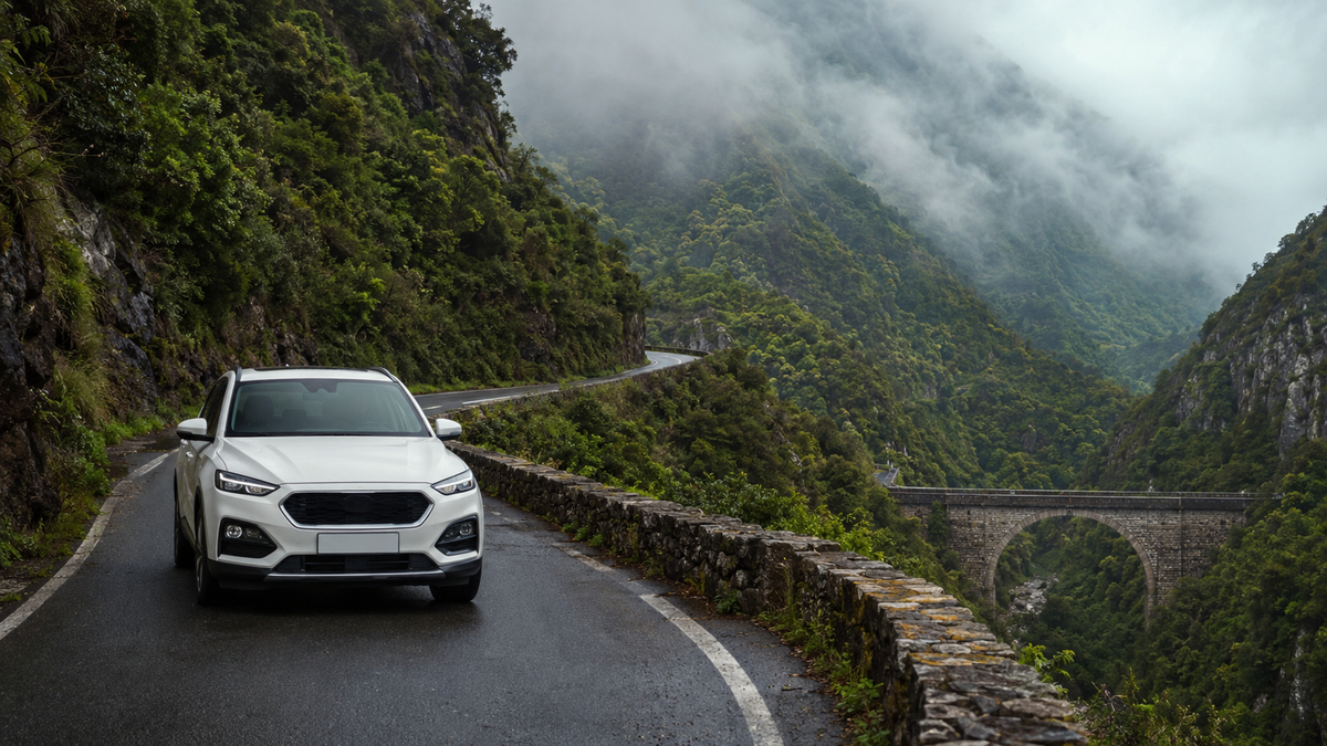 A crossover on a mountain road in Adjara above a forested valley.