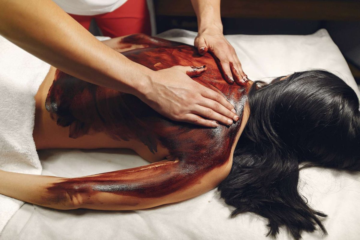 A massage therapist gives a back massage with chocolate.