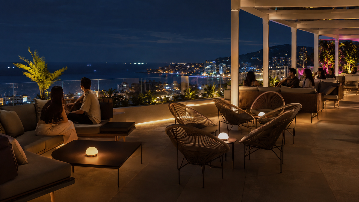 A rooftop lounge in Batumi at night with a sea view and city lights.