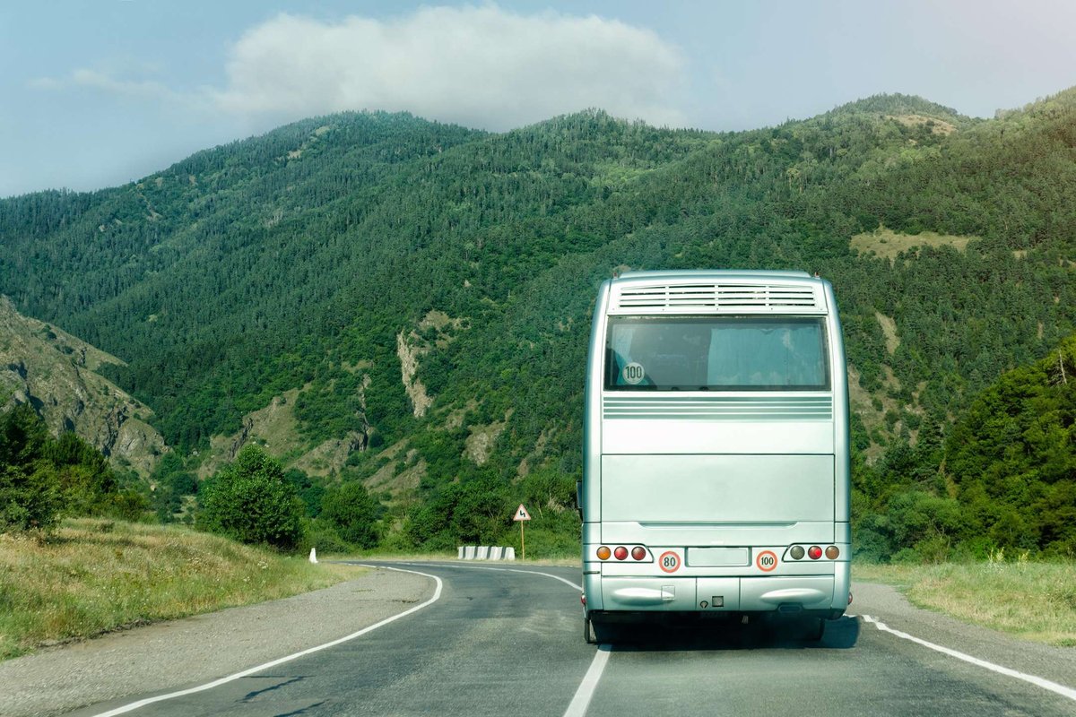 A tourist bus on a road among green mountains