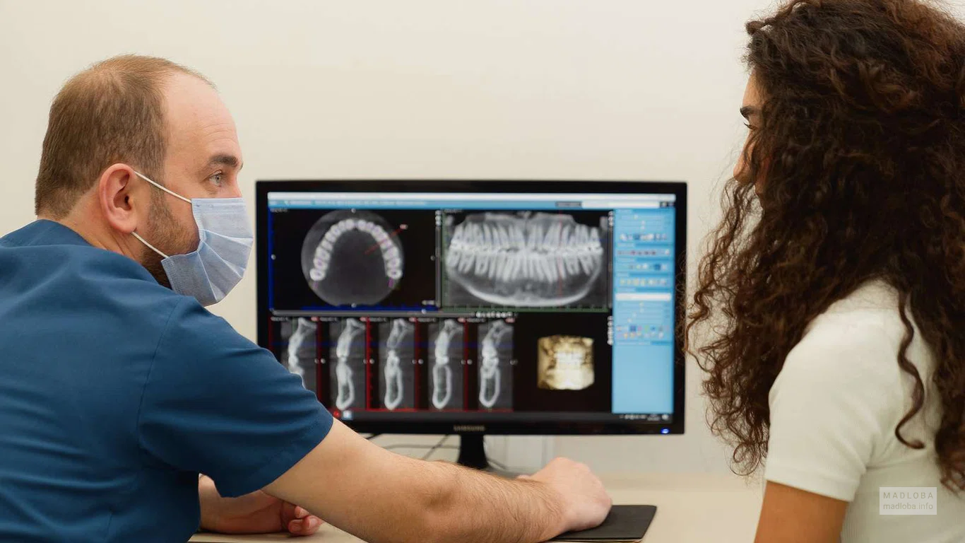 Стоматолог с пациенткой рассматривают снимки зубов