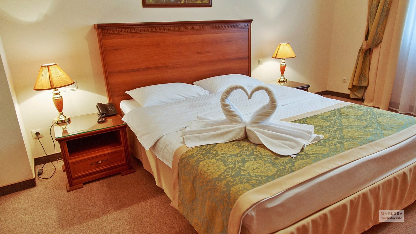 Лебеди из полотенец на кровати в номере отеля Amadeus