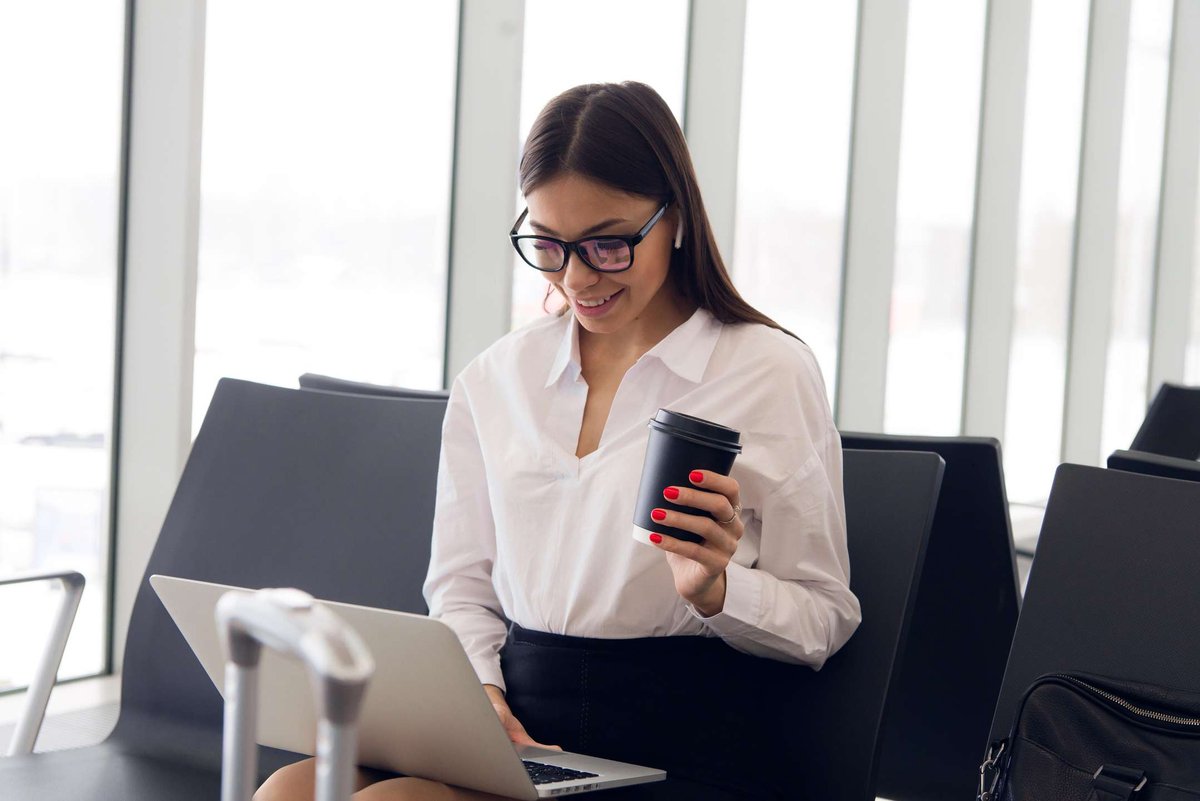 Beautiful businesswoman working on laptop while waiting for her flight at the airport