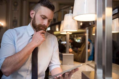 A businessman, cutting his beard, thinks before making a decision