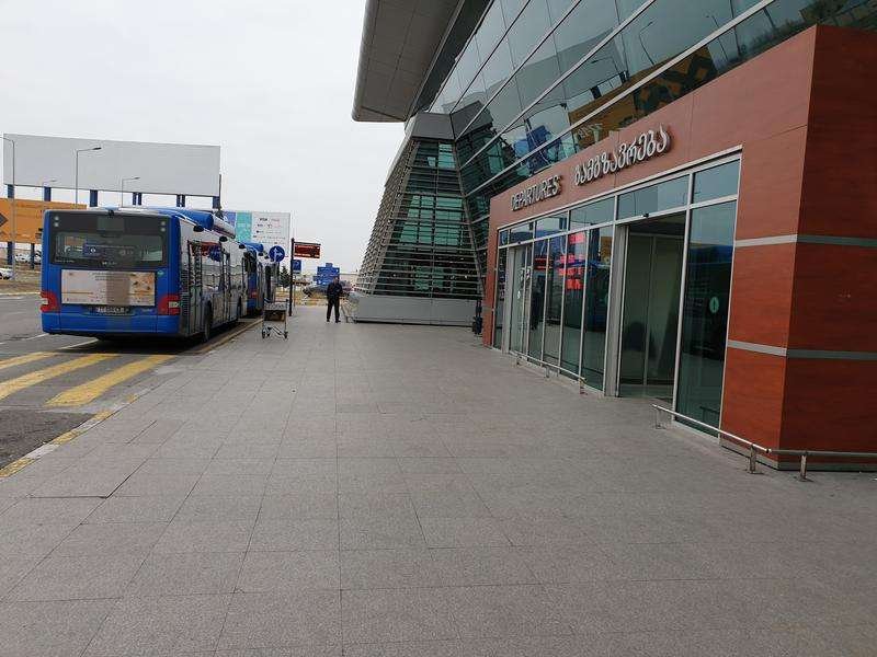 Blue passenger buses are parked at the terminal of Tbilisi International Airport.
