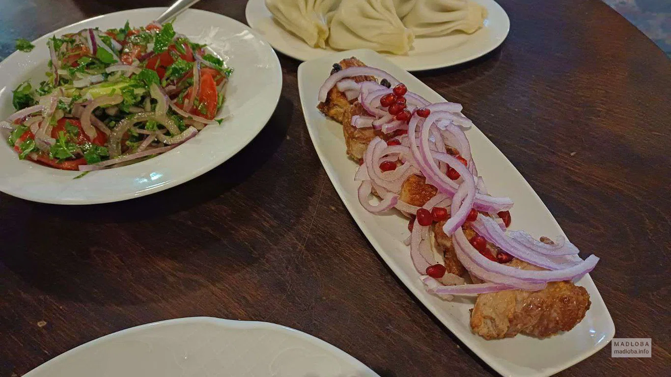 овощной салат, шашлык и хинкали на столе ресторана Brauhaus Tiflisi