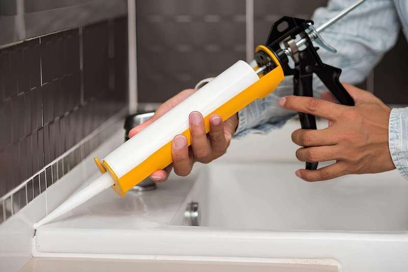 A person applying silicone sealant.