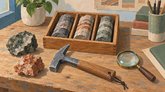 Иллюстрация образцов горных пород и керна в деревянном лотке. Рядом лежат геологический молоток и лупа.
