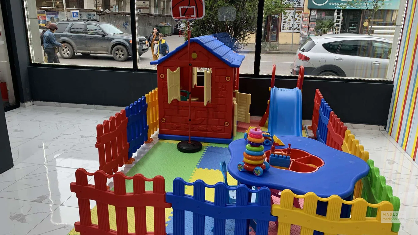 Игровая зона с ярким домиком, огороженная разноцветным забором