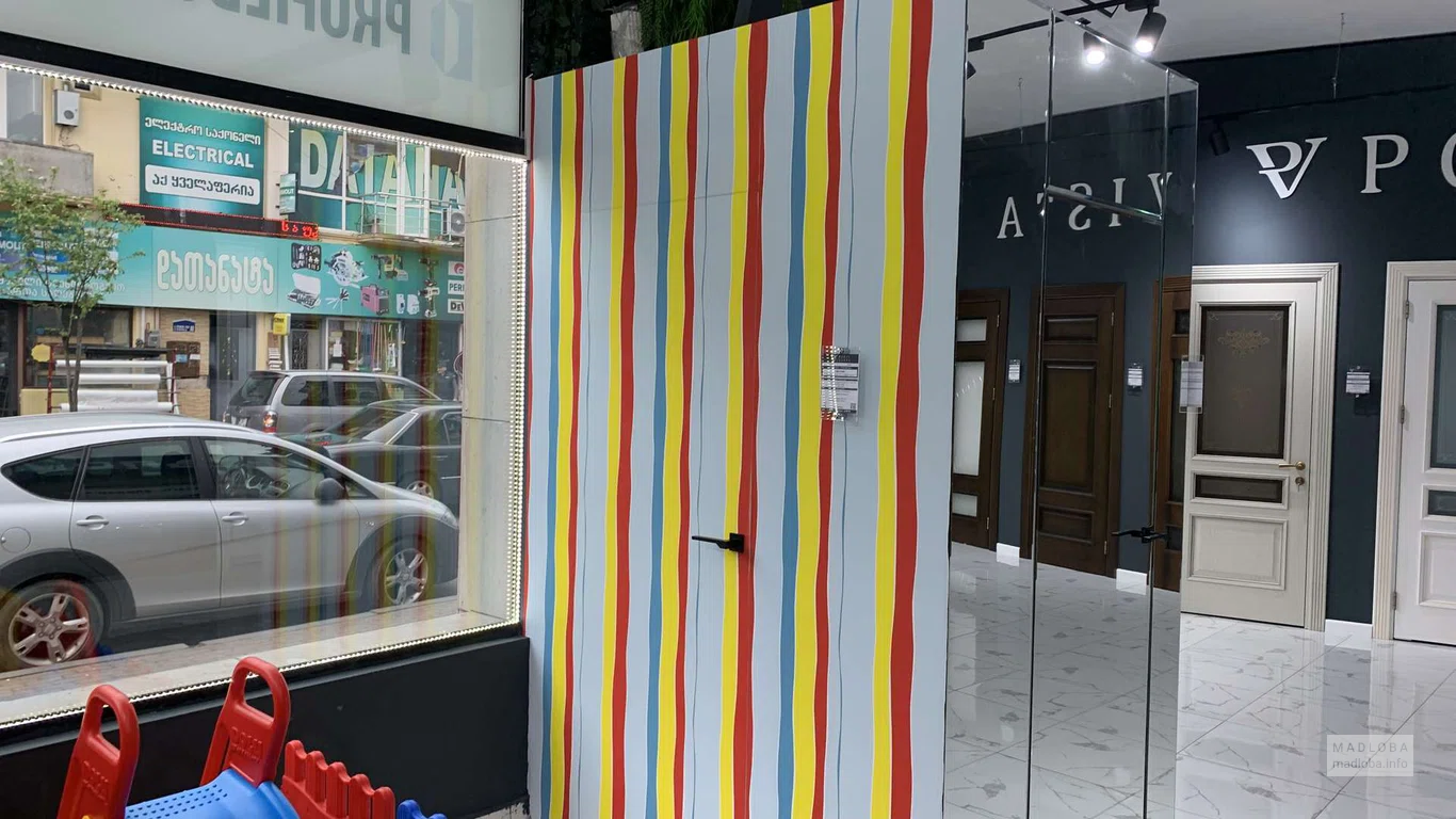 Яркая дверь с цветными вертикальными полосами и черной ручкой