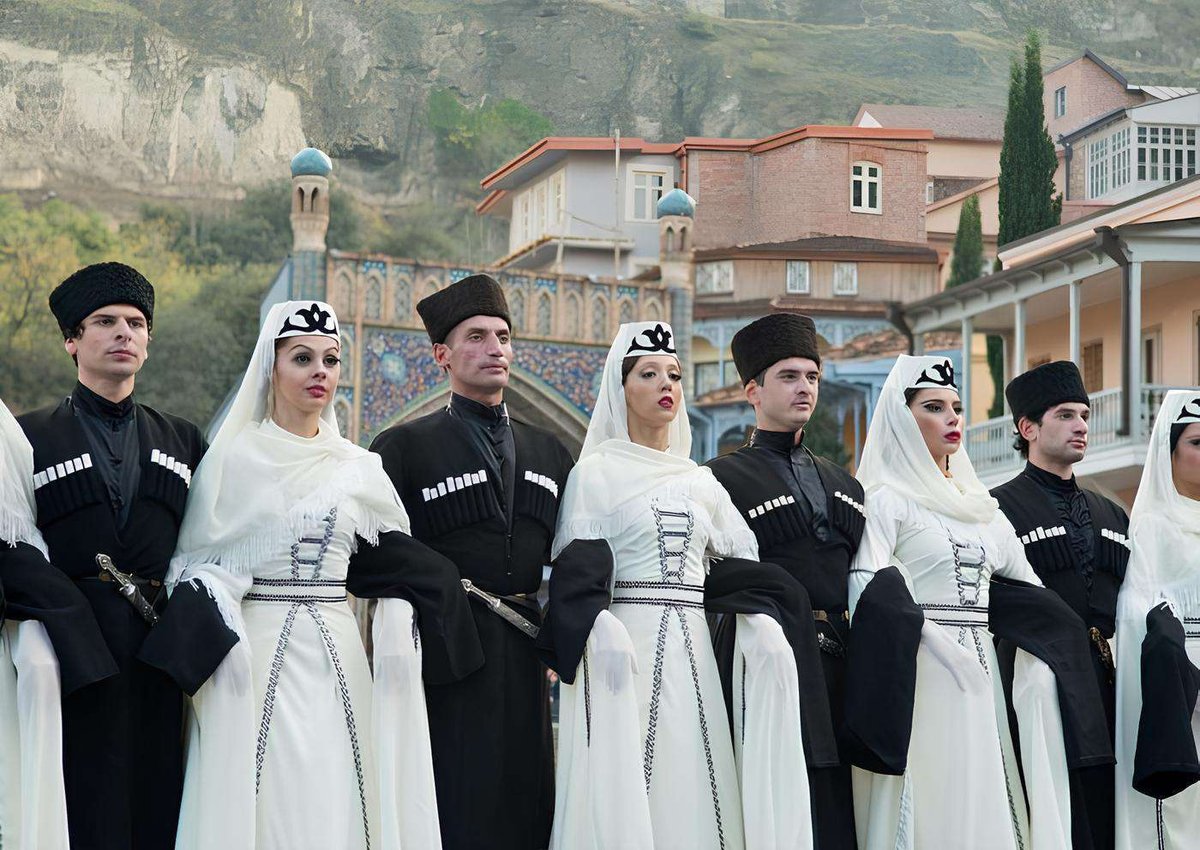 Men and women in national Georgian clothing against the backdrop of the streets of Old Tbilisi