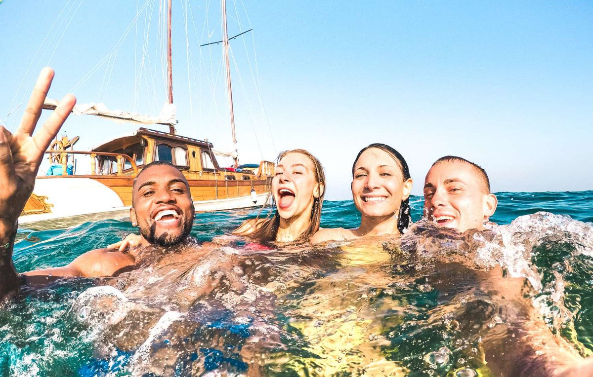 Friends taking selfie and sailing on a sailboat on the sea