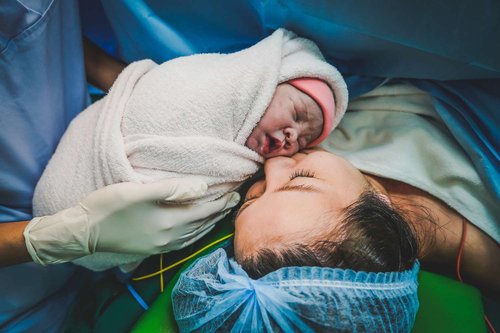 Mother kisses her newborn baby