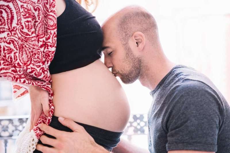 A man kisses a pregnant woman's belly