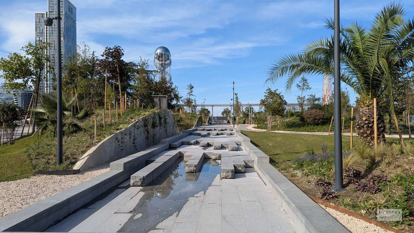 Широкая дорожка ведёт к центру New Park. На заднем плане видна Алфавитная башня — символ побережья Батуми.
