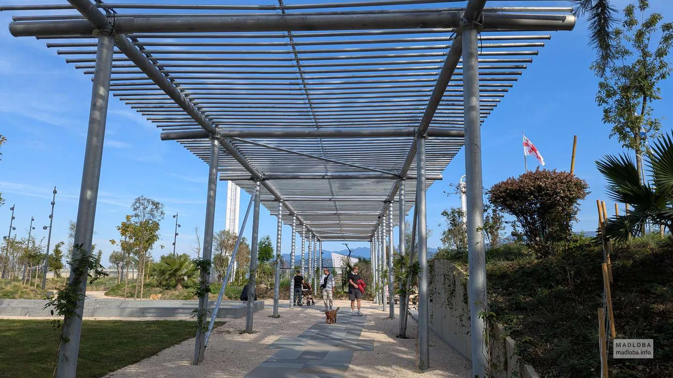 Металлическая конструкция перголы создаёт игру света и тени, защищая от солнца и формируя акцент парка.