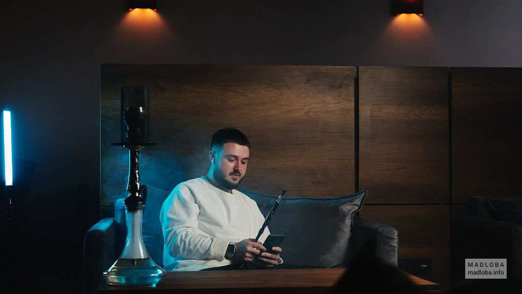 молодой человек курит кальян "Nuahule Smoke" в Батуми