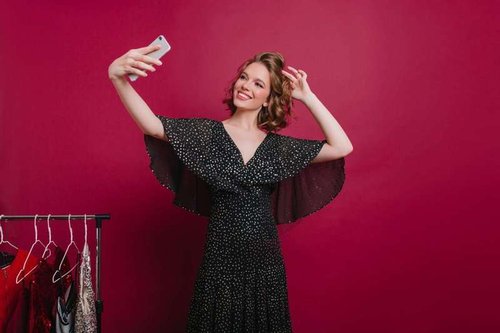 A charming smiling girl takes a selfie in a clothing boutique