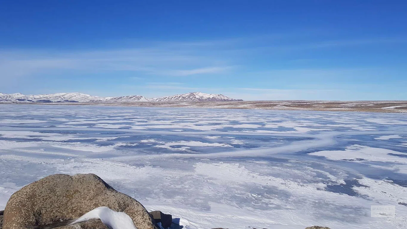 Зимний пейзаж на замерзшем озере Гохнари с горами на горизонте