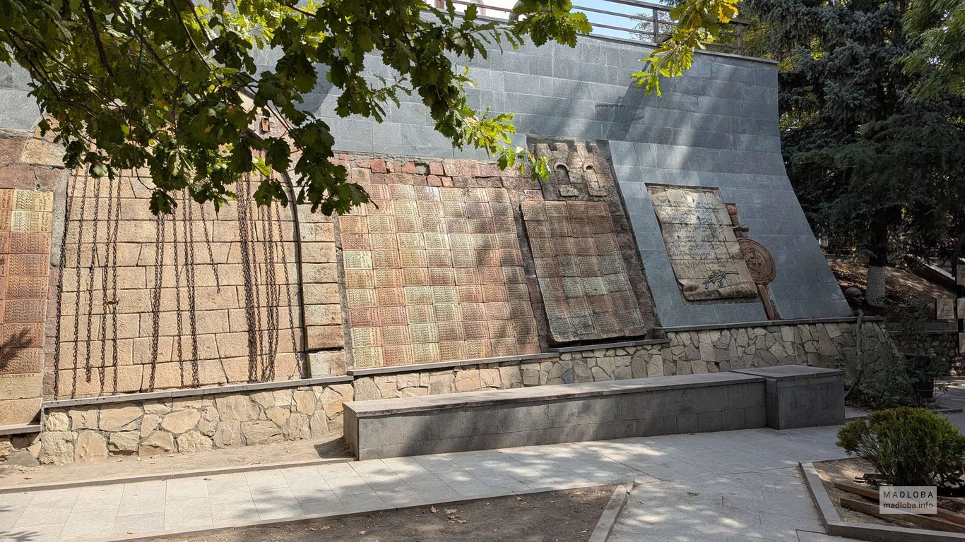 Каменная стена с барельефами и табличками в парке 9 апреля