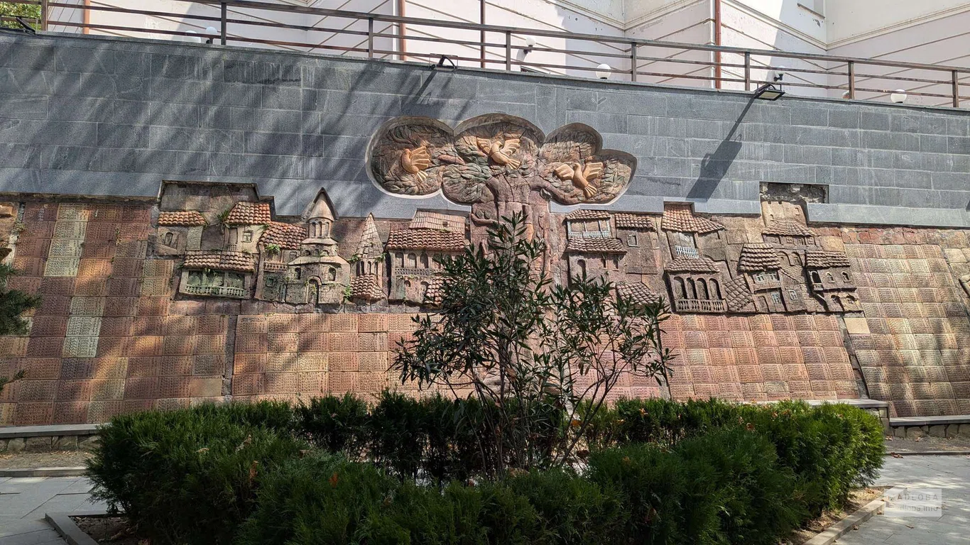 Каменная стена с барельефами и табличками в парке 9 апреля