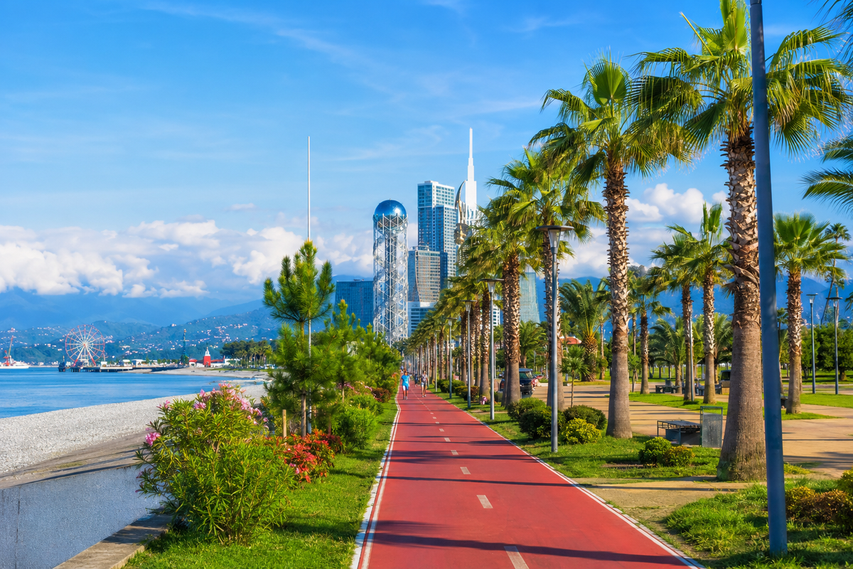 A sunny coastal promenade in Batumi with palm trees, bike paths, greenery and sea views, showing how city walks here easily turn into a half-day seaside escape.