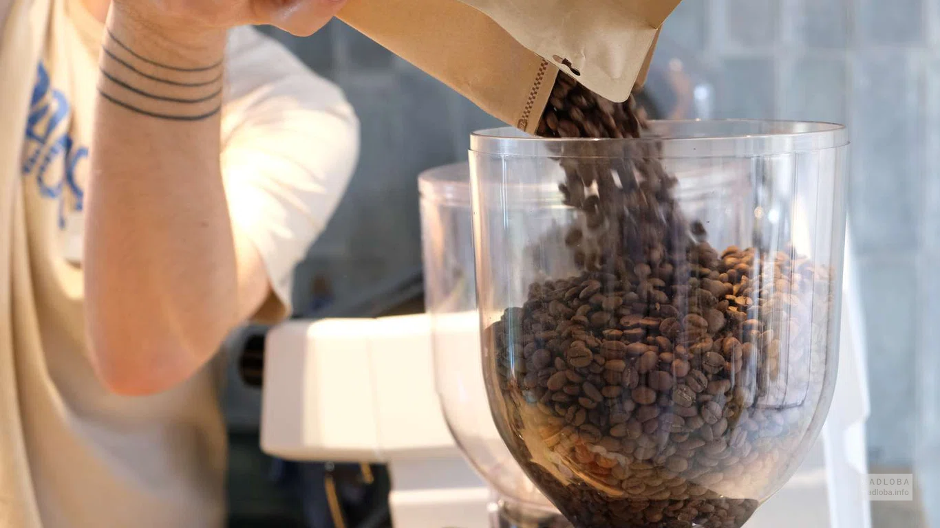 Бариста засыпает кофейные зерна в кофемашину