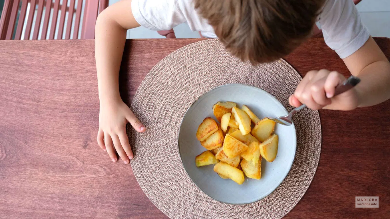 Ребенок кушает жареный картофель