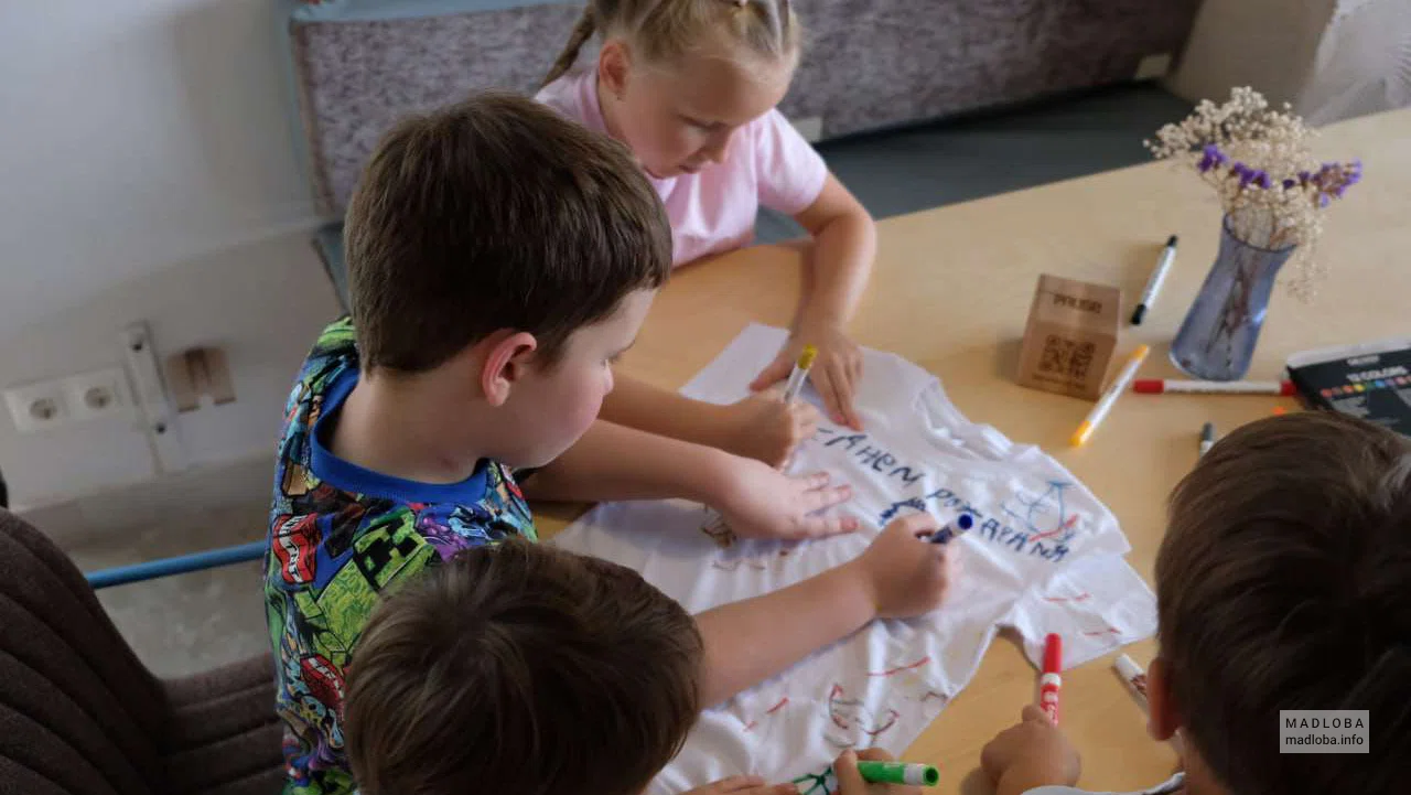 Дети пишут пожелания на футболке