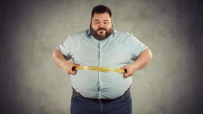 A fat man measures his belly