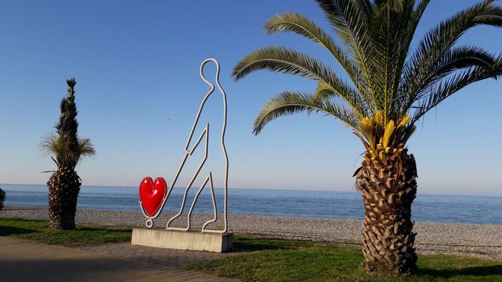 Скульптура "Человек везёт красное сердце на тележке"
