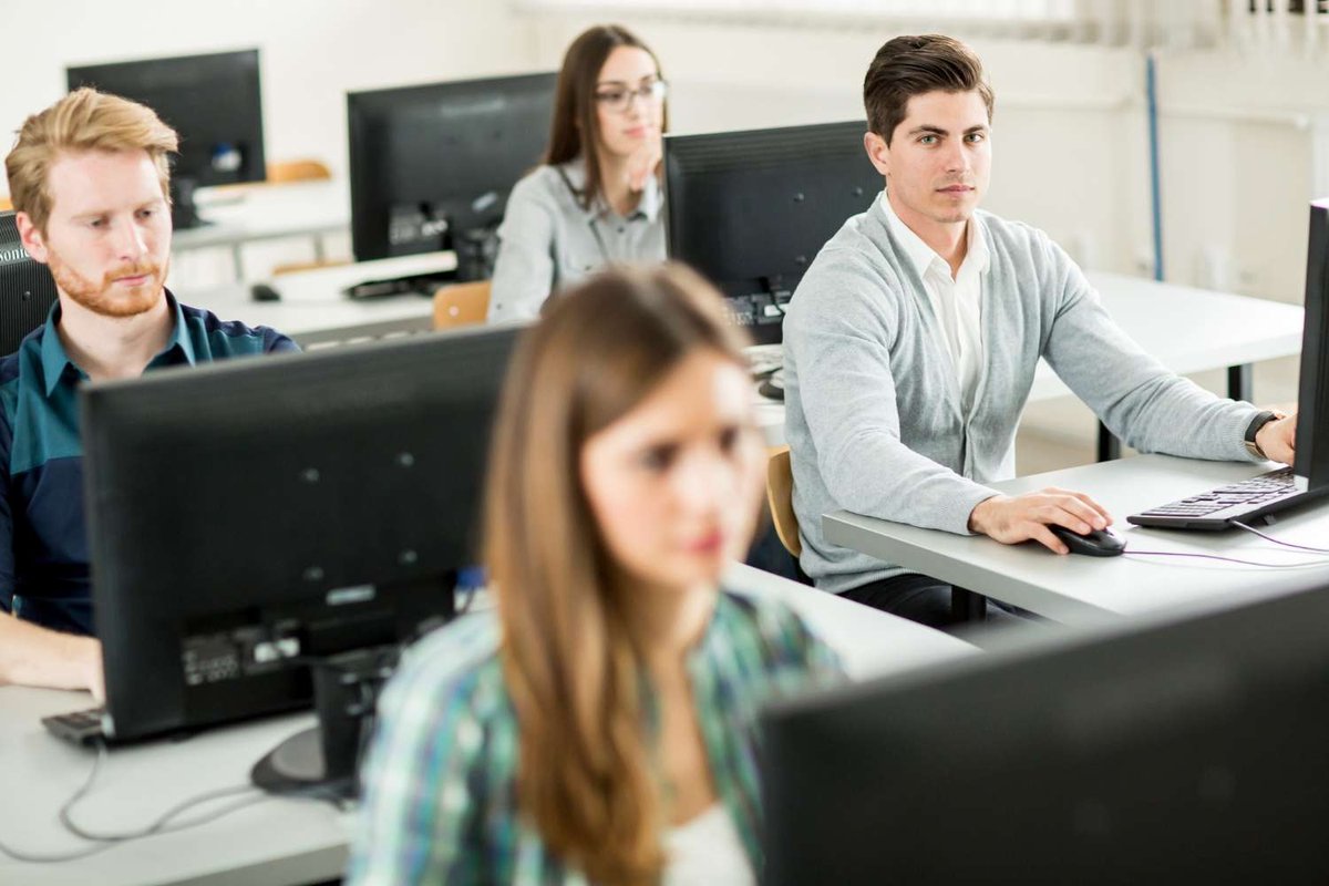 Students working at desktop computers in rows during a classroom coding session — illustrating TBC Tech School and IT classes for students in Georgia.