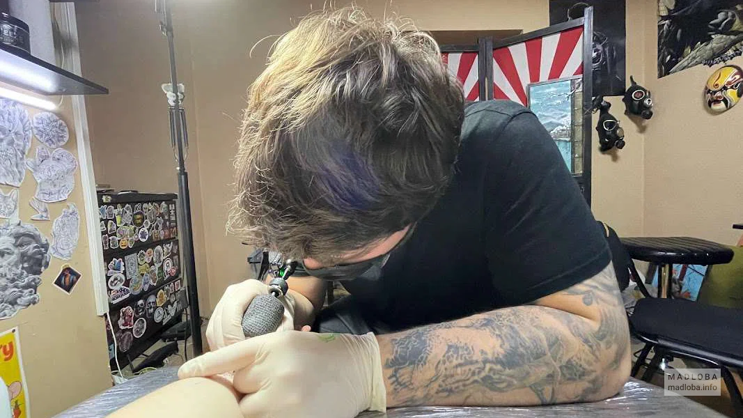 мастер набивает тату в студии Painful Art