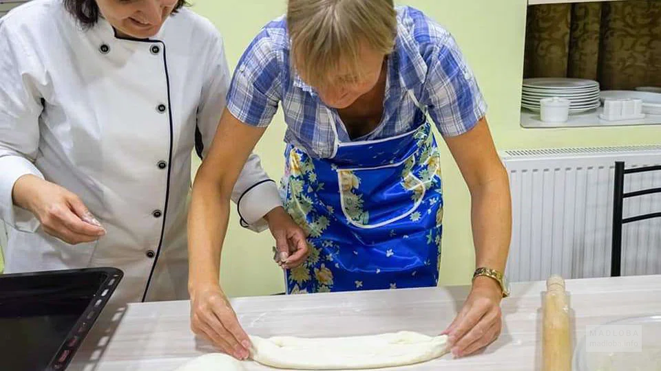 Женщина учится делать "лодочку" из теста для хачапури по Аджарски в Tasty Georgia Culinary Studio