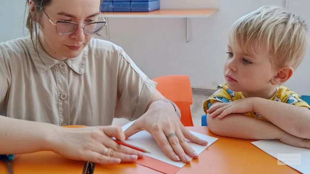 Воспитатель учит ребенка складывать оригами