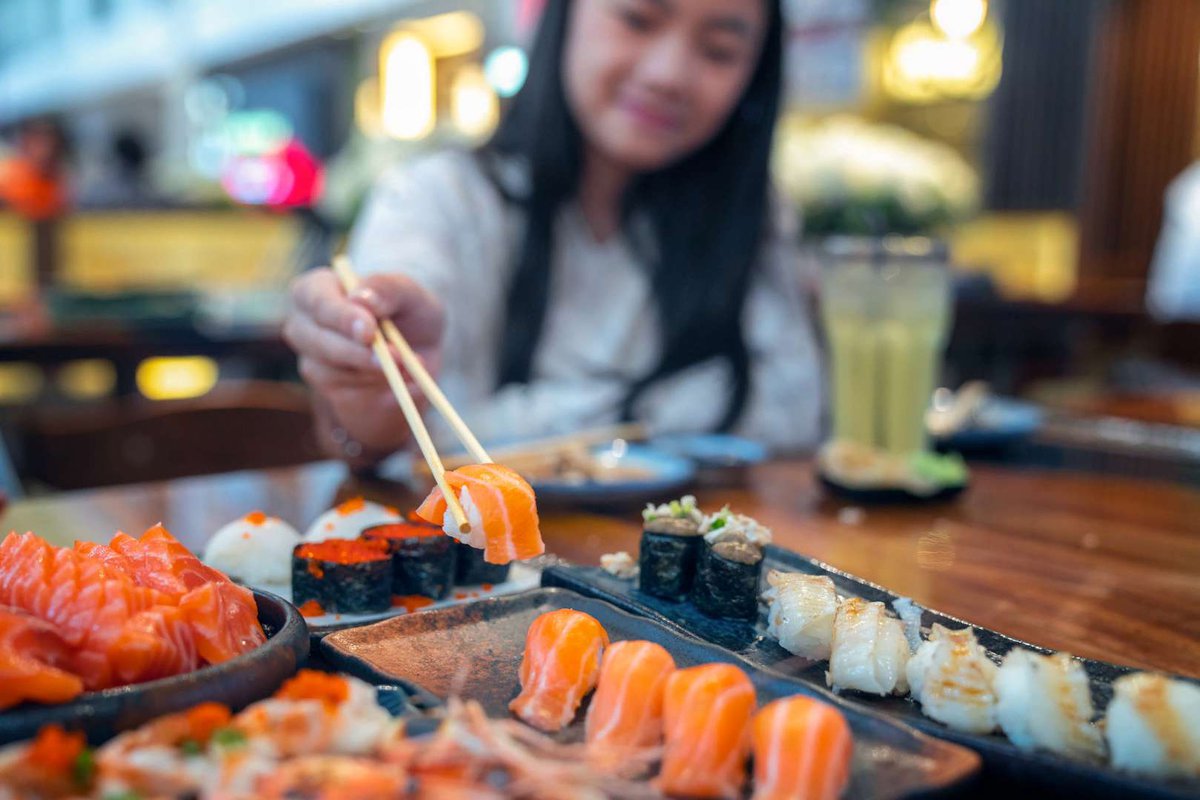 Девушка пробует роллы в суши-баре