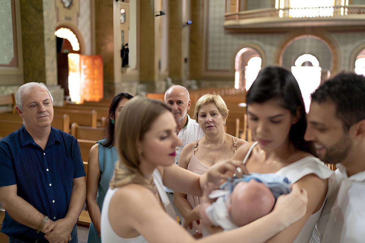 baptism of a baby in a church surrounded by relatives and godparents
