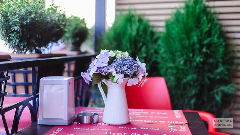 Кувшин с цветами на уличном столике Restaurant Bellissimo