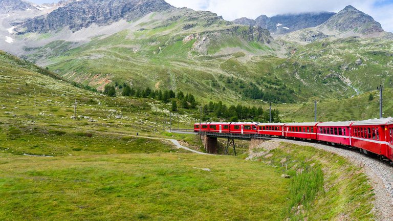 Яркий красный поезд на фоне гор