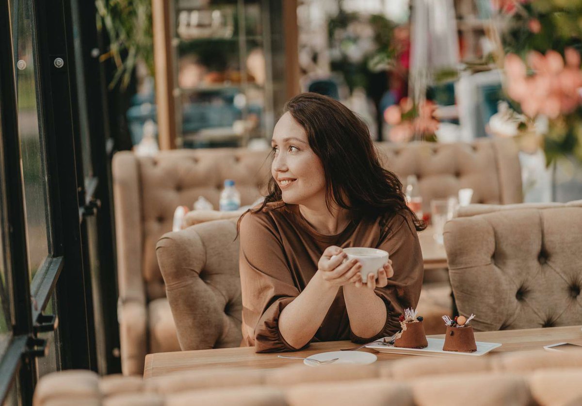 A girl in a cozy cafe enjoys coffee and dessert