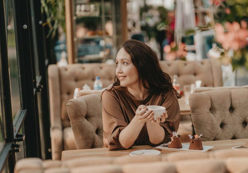 Девушка в уютном кафе наслаждается кофе и десертом