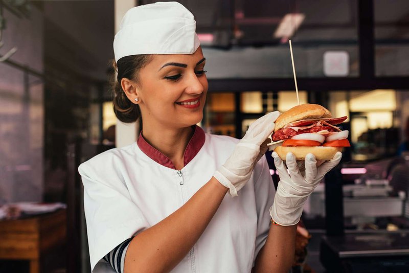 The chef is a woman with a ready-made burger