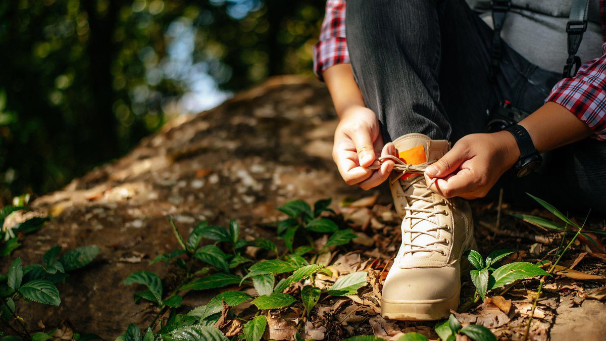 close-up-hand-young-man-sitting-tying-shoelaces-during-walking-trail-copy-space.jpg